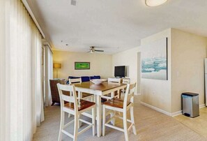 A dining area with a table and chairs, a television, and a painting on the wall. - Rainbow Cove condo w/WIFI, W/D, walk to restaurants & entertainment (Dewey Beach)