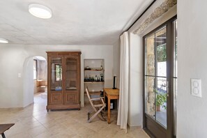 Une pièce comprenant un meuble en bois, un bureau, une chaise et une grande fenêtre avec des rideaux.