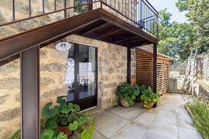 Un edificio de piedra con un balcón, plantas en macetas y una puerta.