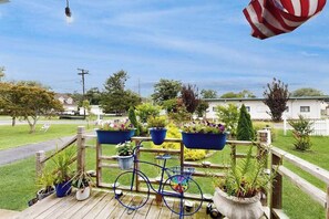 Eine Holzterrasse mit einem Fahrrad, Topfpflanzen und Blick auf ein Wohngebiet.