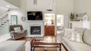 Una sala de estar con chimenea, televisor y escalera.