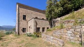 Un edificio de piedra con terraza, asientos al aire libre y vistas a las montañas.