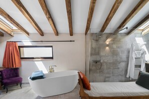 Ein modernes Badezimmer mit einer freistehenden Badewanne, einer Dusche und einem Fenster.
