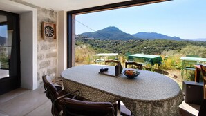 Un área de comedor con una mesa, sillas y vistas a un paisaje montañoso.