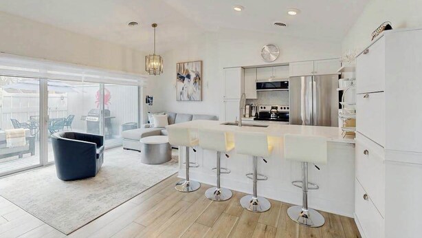 Una cocina moderna con barra, ventanas amplias y comedor con sofá y sillas.