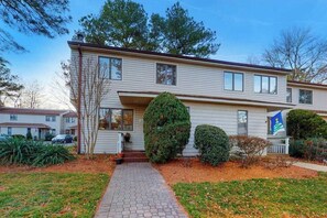 A two-story house with a front porch, a pathway leading to the entrance, and a flag on the right side. - Bethany Pines Townhouse w/Free WiFi, Private Washer and Dryer, & Shared Pool (Bethany Beach)