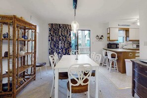 A compact kitchen with a dining area, white furniture, and a wooden bookshelf. - Bethany Pines Townhouse w/Free WiFi, Private Washer and Dryer, & Shared Pool (Bethany Beach)