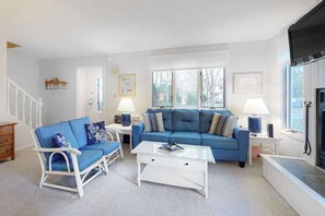 A living room with a blue sofa, white coffee table, and a fireplace. - Bethany Pines Townhouse w/Free WiFi, Private Washer and Dryer, & Shared Pool (Bethany Beach)