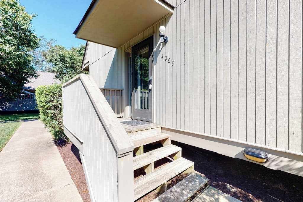 A house with a wooden front porch, a door, and a mailbox.