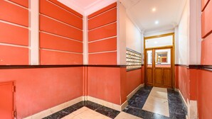 A hallway with red walls, black and beige tiled flooring, and a wooden door at the end. - (VAL203E) 1 bedroom apartment in the center of Madrid (Madrid)