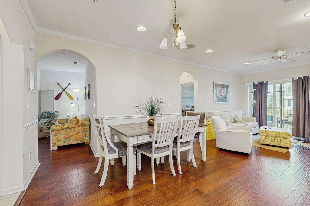 A spacious living room with a dining area, a sofa, a chair, and a ceiling fan.