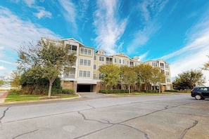 A multi-story residential building with a parking lot in front.