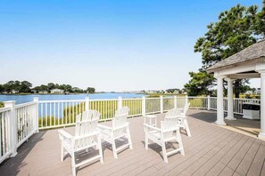 A deck with white chairs and a gazebo overlooking a lake. - Bayside Bethany Lakes retreat with pool access, screened patio & fast WiFi (Ocean View)