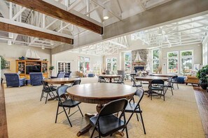 A spacious indoor area with multiple tables and chairs, a fireplace, and large windows allowing natural light. - Bayside Bethany Lakes retreat with pool access, screened patio & fast WiFi (Ocean View)