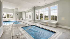 En swimmingpool med vippe, store vinduer og udsigt til det fri.