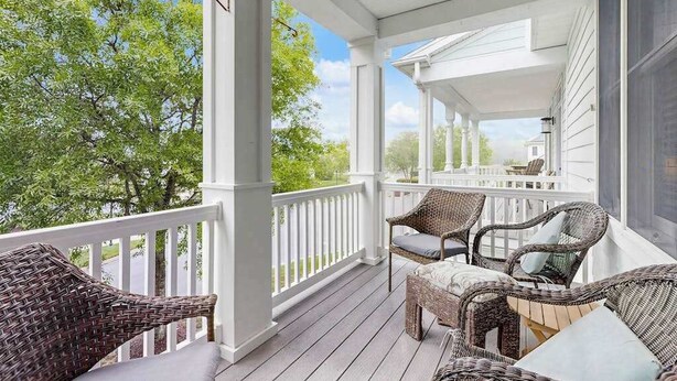 A covered porch with wicker furniture and a view of trees. - Three-Story Bayside Resort Retreat W/ Shared Pool/Hot Tub, Balcony & Central AC (Selbyville)