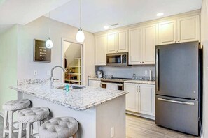 A kitchen with a central island, stainless steel appliances, and a light-colored backsplash. - Sea Colony Condo w/ Free WiFi, Central AC, Shared Pools, & Hot Tubs (Bethany Beach)