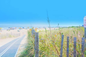 Ein Strand mit Holzzaun, einer Straße und einem Schild.