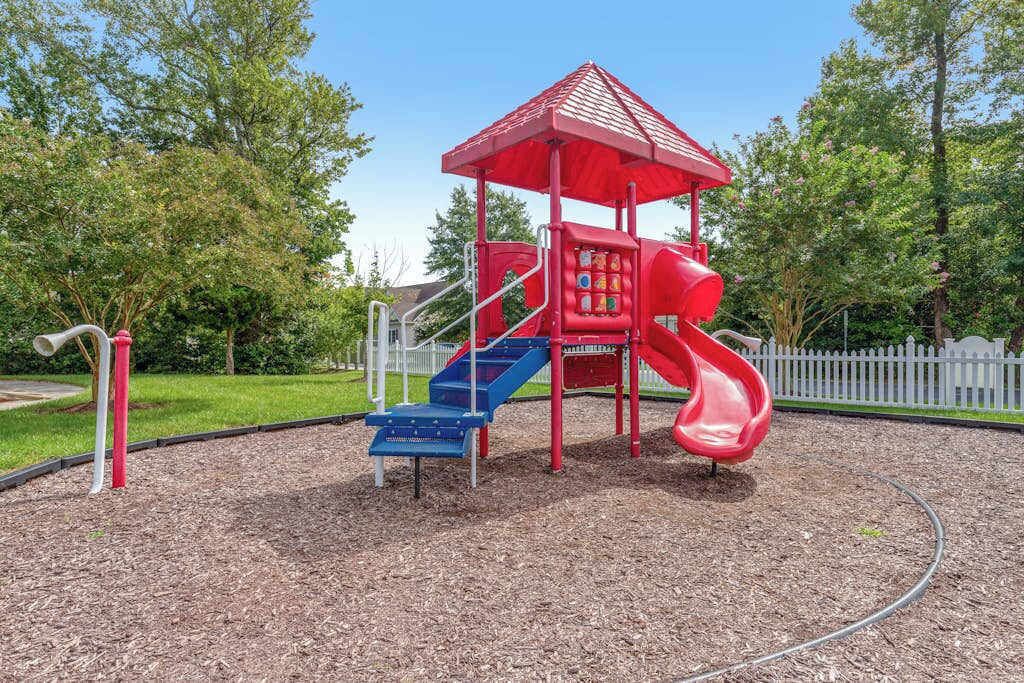 A playground with a red slide and blue steps.