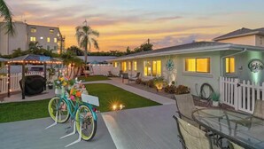 Een woonhuis met een terras, een fiets en een huis met warme verlichting bij zonsondergang.