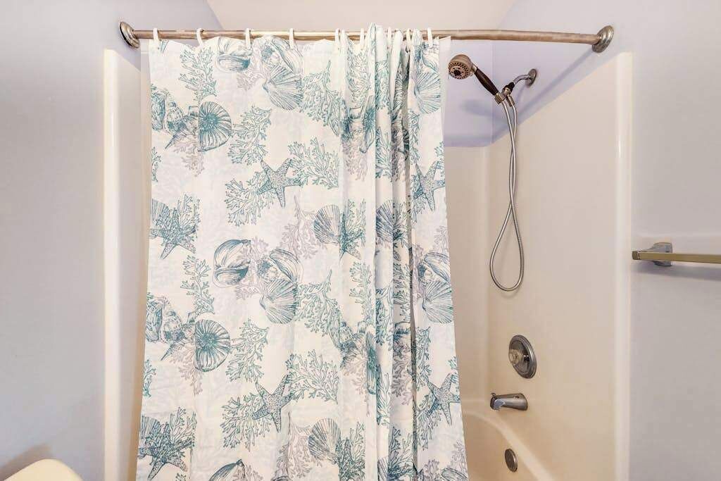 A shower curtain with a floral pattern, a showerhead, and a towel rack.