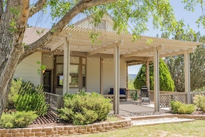 A covered patio with a pergola, outdoor seating, and a view of a house. - Ranch Escape | Near Verde River, 2 King Suites, Sleeps 9 (Camp Verde)