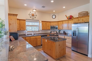 A kitchen with wooden cabinets, granite countertops, stainless steel appliances, and a window. - Ranch Escape | Near Verde River, 2 King Suites, Sleeps 9 (Camp Verde)