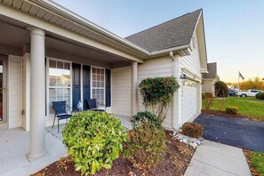 A single-story house with a covered porch, a small garden, and a flag in the background. - Lord Baltimore Landing house w/shared pool, free WiFi, central AC, private W/D (Ocean View)