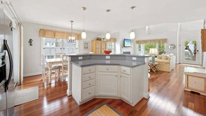 Una cocina moderna con una isla central, mesa de comedor de madera e iluminación colgante.