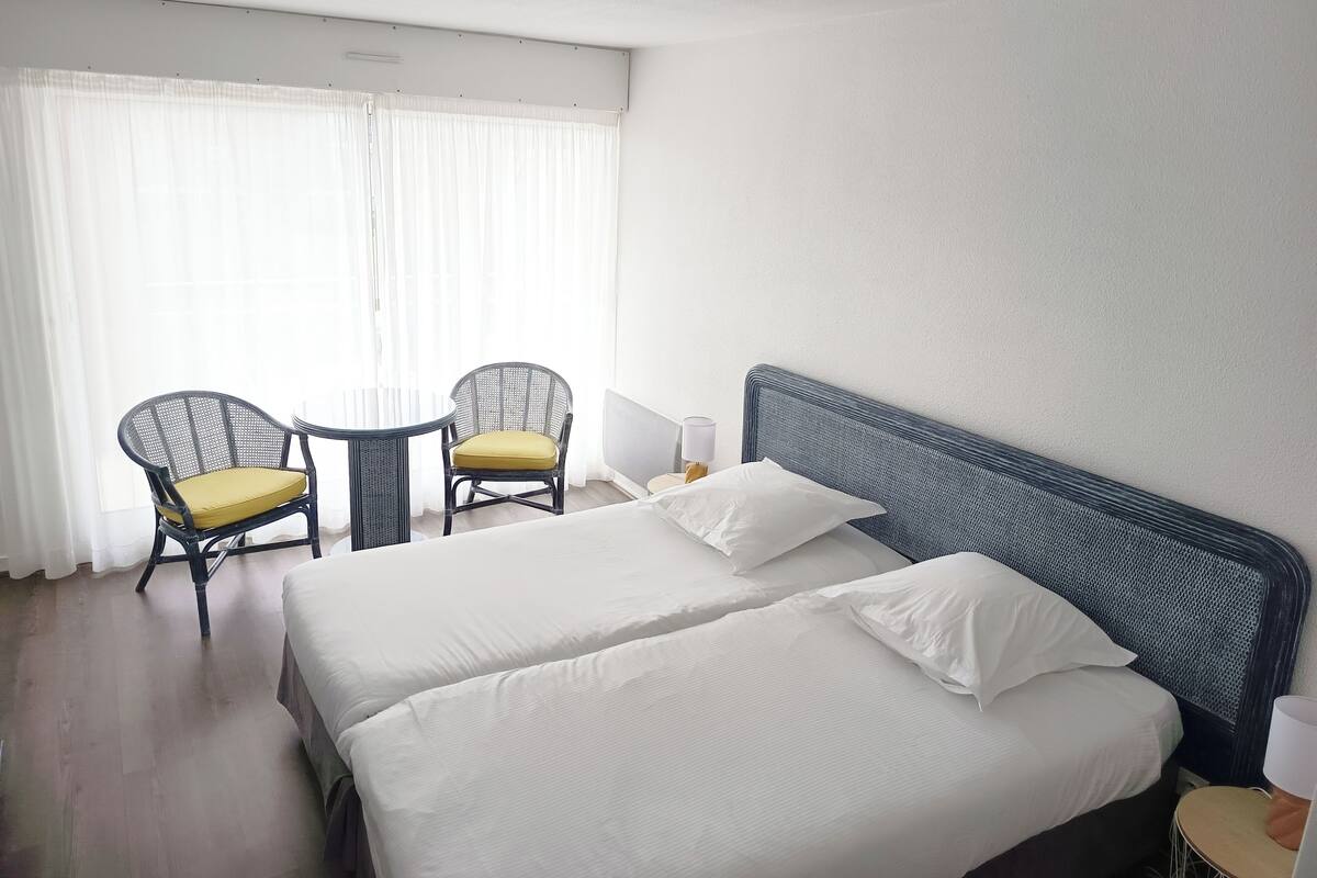 Een hotelkamer met een bed, twee stoelen, een tafeltje en een lamp.