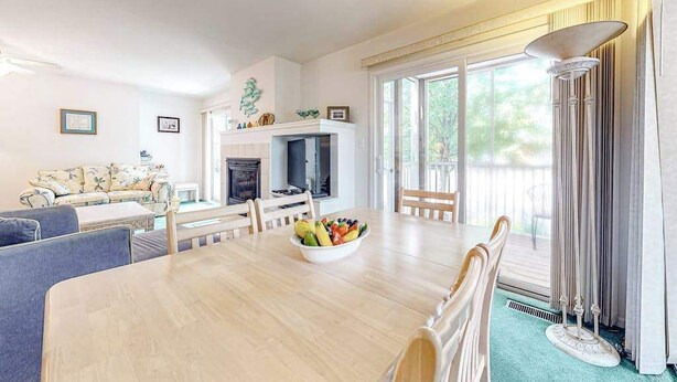 A living room with a fireplace, a dining table with chairs, a sofa, and a large window with curtains. - Sea Colony Tennis condo w/ central AC and access to pool and fitness center (Bethany Beach)