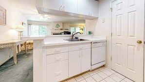 A kitchen with white cabinets, a sink, and a dishwasher. - Sea Colony Tennis condo w/ central AC and access to pool and fitness center (Bethany Beach)