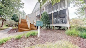 A two-story building with a wooden staircase leading to a porch, surrounded by trees and a sign indicating 'Vista #2'. - Sea Colony Tennis condo w/ central AC and access to pool and fitness center (Bethany Beach)