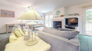 A living room with a sofa, a table with a lamp, a fireplace, and a television. - Sea Colony Tennis condo w/ central AC and access to pool and fitness center (Bethany Beach)