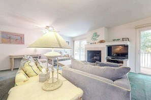 Ein Wohnzimmer mit einer Couch, einem Tisch mit Lampe, einem Kamin und einem Fernseher.
