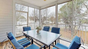 A covered patio with a table and chairs, large windows, and a ceiling fan. - Coastal Retreat I Resort Amenities, Championship Golf, Indoor & Outdoor Pools (Ocean View)