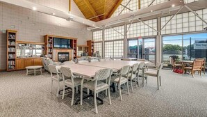 A spacious room with a large table, chairs, bookshelves, and a fireplace. - Coastal Retreat I Resort Amenities, Championship Golf, Indoor & Outdoor Pools (Ocean View)