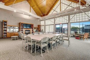 A spacious room with a large table, chairs, bookshelves, and a fireplace.