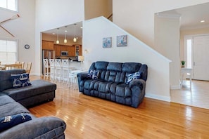 A modern living room with a sectional sofa, a dining area, and a kitchen in the background.