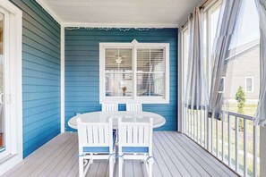 A covered porch with a table and chairs, a window with blinds, and a view of a house. - Bayside Resort home close to the beach with shared pools & hot tub - dogs OK (Selbyville)