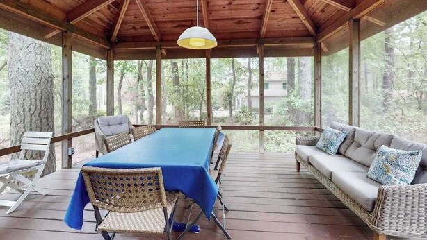 Un espacio exterior techado con una mesa, sillas, un sofá y una lámpara colgante.
