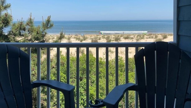 Ein Balkon mit Blick auf den Strand, Stühlen und einem Geländer.