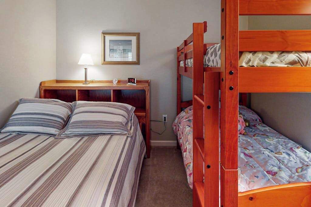 A bedroom with two beds, a wooden nightstand, a lamp, and a framed picture on the wall.