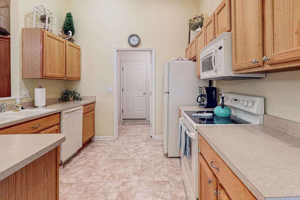 Una cocina con armarios de madera, un microondas, una estufa y un refrigerador.