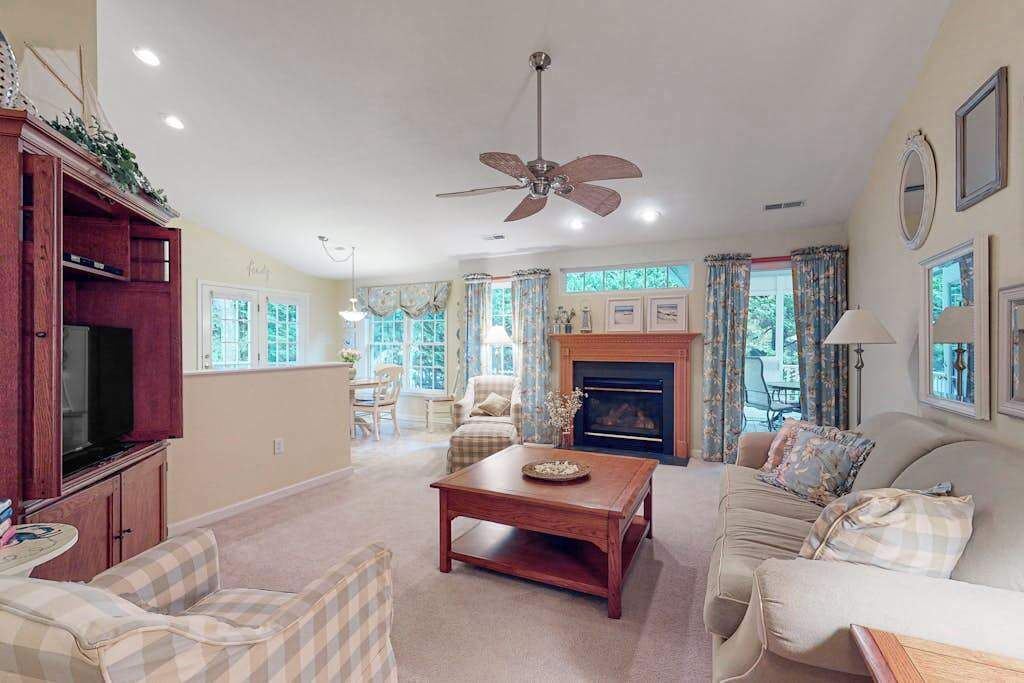 A living room with a fireplace, a ceiling fan, and a television.