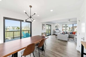 A spacious living area with a wooden dining table, a gray sofa, and a view of the outdoors. - Amazing home near beach, shopping & Ocean City - dog-friendly, central AC & W/D (Fenwick Island)