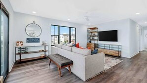 Un salon moderne avec un canapé, une table basse, un téléviseur et une bibliothèque.