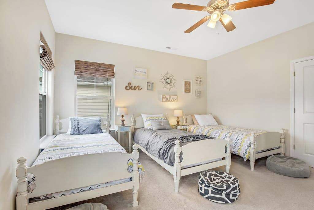 A bedroom with two beds, a ceiling fan, and wall decorations.