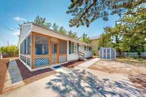 Une maison de plain-pied dotée d’une grande véranda à l’avant, d’un espace extérieur couvert et d’un petit abri de jardin.