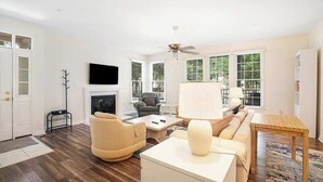 A living room with a fireplace, a sofa, a coffee table, a lamp, and a television. - Bear Trap Dunes 1st floor condo w/ central AC, private W/D, and gas fireplace (Ocean View)